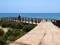 Adult couple walking on a wooden walkway that leads directly to the beach