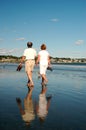 An adult couple walks along the shoreline Royalty Free Stock Photo