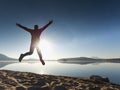 Adult crazy man jumps near water on against red sunset. Empty beach Royalty Free Stock Photo