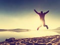 Adult crazy man jumps near water on against red sunset. Empty beach Royalty Free Stock Photo