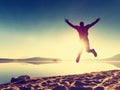 Adult crazy man jumps near water on against red sunset. Empty beach Royalty Free Stock Photo