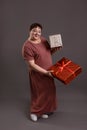 adult curvy woman holding gifts for Christmas on neutral grey background Royalty Free Stock Photo