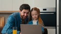 Adult dad explain teaching small kid girl help with using laptop at home kitchen. Daughter learning typing surfing Royalty Free Stock Photo