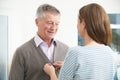 Adult Daughter Helping Senior Man To Button Cardigan