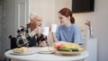 An adult daughter and her elderly father drink tea and communicate cutely