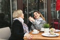 Adult daughter holds her mother's hand and smiles. Emotions of relatives in the cafe