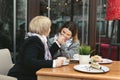 An adult daughter kisses her mother's hand and smiles. Emotions of relatives in the cafe