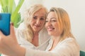 Adult daughter and senior mom taking selfie together Royalty Free Stock Photo