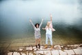 Adult daughter spending time with her mother, having fun, jumping. Mom and daughter outdoors, on walk by reservoir Royalty Free Stock Photo