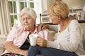 Adult Daughter Visiting Unhappy Senior Mother Sitting On Sofa At Home