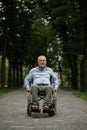 Adult disabled man in wheelchair walking in park Royalty Free Stock Photo