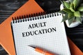 ADULT EDUCATION - words in white notebook on dark wooden background with cactus and pen Royalty Free Stock Photo