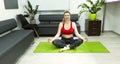 An adult experienced athletic woman sits in a lotus position on the rug in the office. Indoor training. Physical education