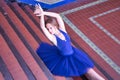 Adult female classical ballet dancer in blue tutu doing figures sitting on the steps of a staircase