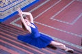 Adult female classical ballet dancer in blue tutu doing figures sitting on the steps of a staircase