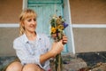 Adult female florist creates a beautiful bouquet of dried flowers. Focus on a bouquet of dried flowers in the hands of a woman