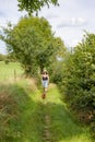 Adult female hiker in summer clothes walking on path with dog between farms Royalty Free Stock Photo