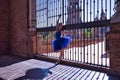 Adult female Hispanic classical ballet dancer in blue tutu making figures on metal gratings against the light