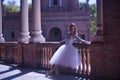 Adult female Hispanic classical ballet dancer making figures leaning on a stone balustrade, wearing a white tutu