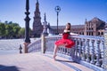 Adult female Hispanic classical ballet dancer in red tutu doing figures leaning on a beautiful tiled balustrade in the middle of a