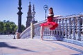 Adult female Hispanic classical ballet dancer in red tutu doing figures leaning on a beautiful tiled balustrade in the middle of a