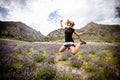 Adult female jumps in a field of purple lupine wildflowers in the June Lake Loops in the Eastern Sierra mountains of California.