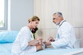 adult female patient with glass of water taking pills from mature male doctor Royalty Free Stock Photo