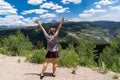Adult female stands with arms raised, back facing viewer, along the Colorado Million Dollar Highway Royalty Free Stock Photo