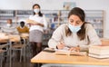 Woman wearing mask studying in public library