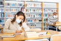 Woman wearing mask studying in public library