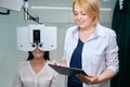 Adult female taking digital refraction test supervised by eye doctor