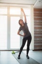 Adult fit slim woman has workout at home. Vertical picture of well-built in good shape female person stretching her body Royalty Free Stock Photo