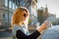 Adult girl in blue sunglassed is looking at the paper map and searching for direction early in the morning in ancient Royalty Free Stock Photo