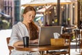 Adult girl working online distant job with laptop in city cafe restaurant browsing website chatting Royalty Free Stock Photo