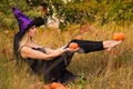 Adult glad girl in witch costume practicing yoga