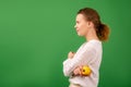 Adult good looking woman in white shirt holds fresh apple on green background. Healthy eating, vegetarianism, healthy appearance Royalty Free Stock Photo