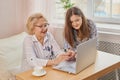 Adult granddaughter teaching her elderly grandmother to use laptop Royalty Free Stock Photo