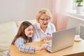 Adult granddaughter teaching her elderly grandmother to use laptop Royalty Free Stock Photo