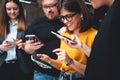 Adult group of happy hipsters stand in line and using in hands modern smartphone