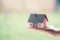 Adult hand is holding red house model, outdoors. Concept for new home, property and estate Royalty Free Stock Photo