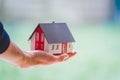 Adult hand is holding red house model, outdoors. Concept for new home, property and estate Royalty Free Stock Photo