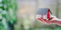 Adult hand is holding red house model, outdoors. Concept for new home, property and estate. Text space Royalty Free Stock Photo