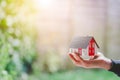 Adult hand is holding red house model, outdoors. Concept for new home, property and estate. Text space Royalty Free Stock Photo