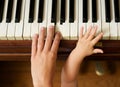 Adult hand playing piano with baby hand