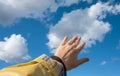 Adult hand reaching out towards the sky. Hand touch the blue sky with clouds Royalty Free Stock Photo