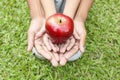 Adult hands holding kid hands with red apple