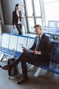 adult handsome businessman reading newspaper while businesswoman walking at departure lounge Royalty Free Stock Photo