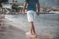 Adult handsome man walking barefoot on the water along the seashore. Famous North Cyprus Beach Background Royalty Free Stock Photo