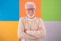 Adult handsome senior man crossed arms looking at camera smiling on colored cute background. Caucasian 70 years old white-haired Royalty Free Stock Photo