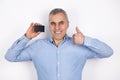 Adult handsome smiling man with grey hair wearing blue shirt holds bank card looks happy showing like sign, standing on Royalty Free Stock Photo